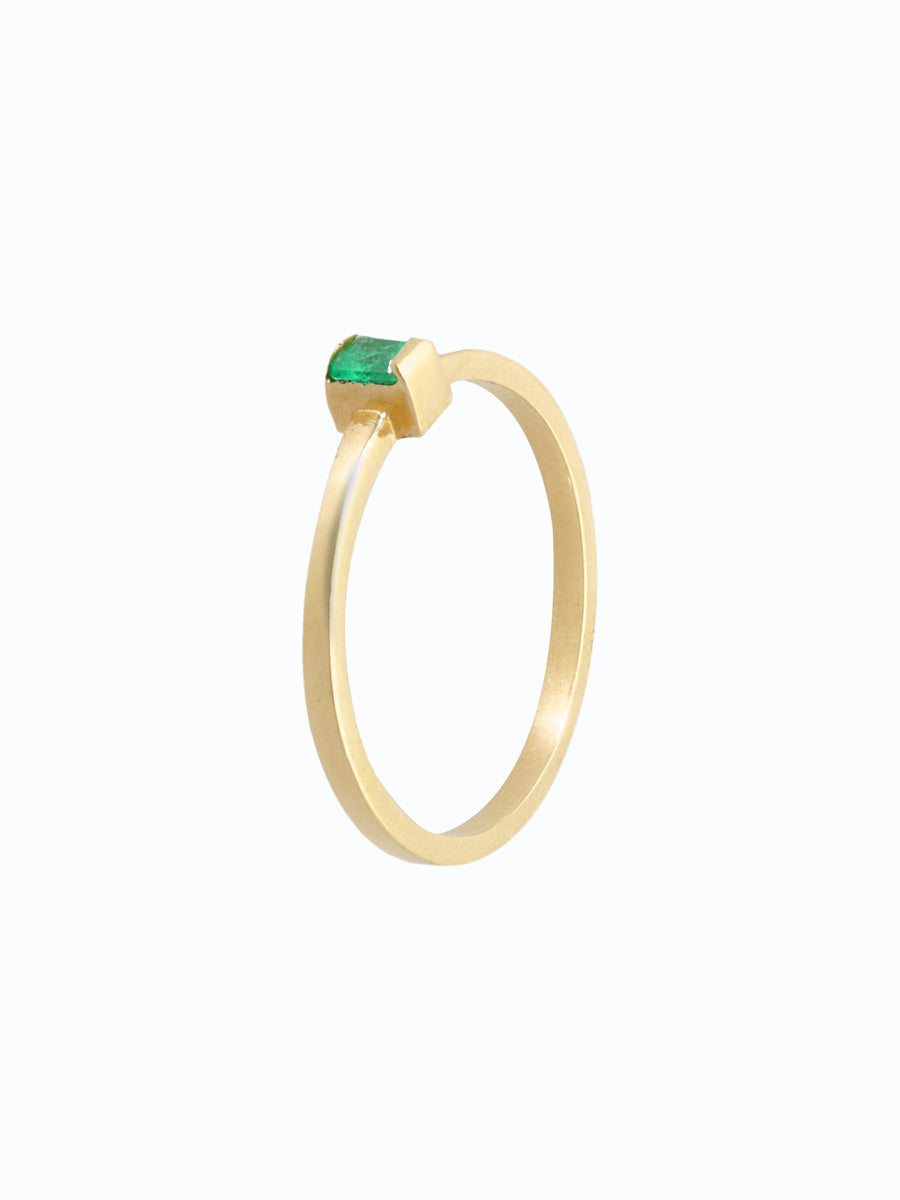 Anillo de oro 18k con esmeralda verde intensa. Corte rectangular, fondo neutro, estilo tradicional.
