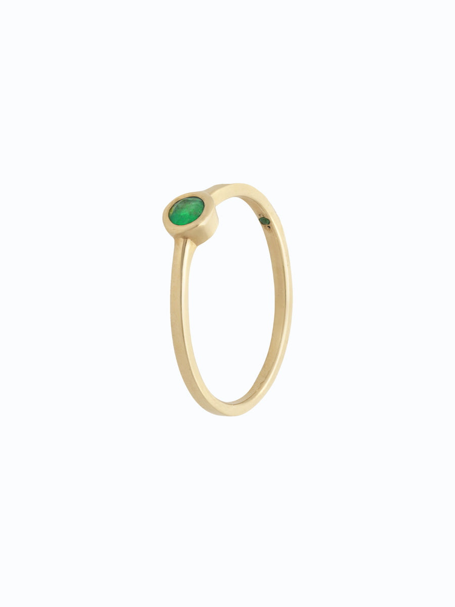 Joya de oro 18k con esmeralda ovalada. Engaste delicado, piedra central en primer plano.