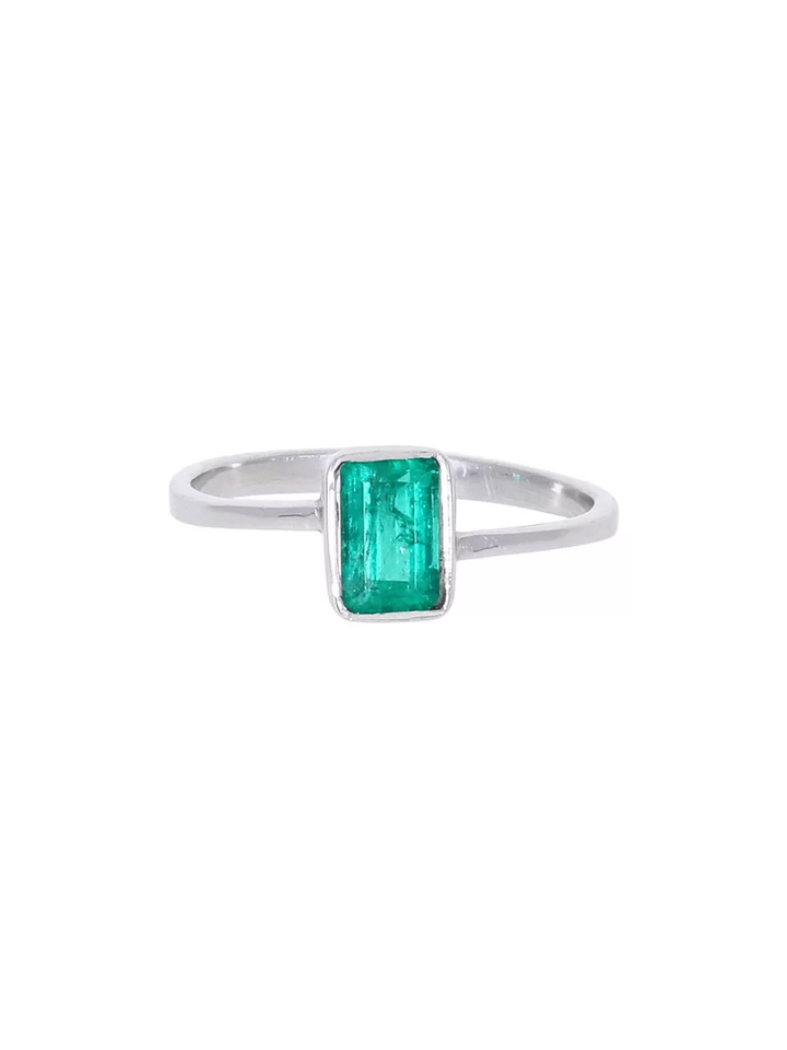 Anillo de oro 18k con anillo de compromiso en oro blanco con esmeralda talla baguette. Fondo neutro, piedra central visibl...