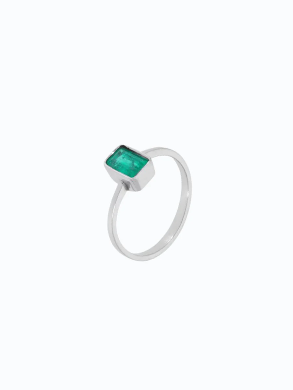 Anillo de oro 18k con anillo de compromiso en oro blanco con esmeralda talla baguette. Fondo neutro, piedra central visibl...
