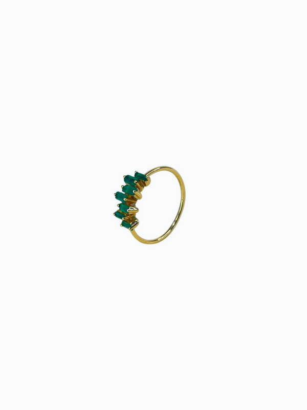Anillo de oro fino con esmeraldas engastadas en forma clásica. Fondo neutro.